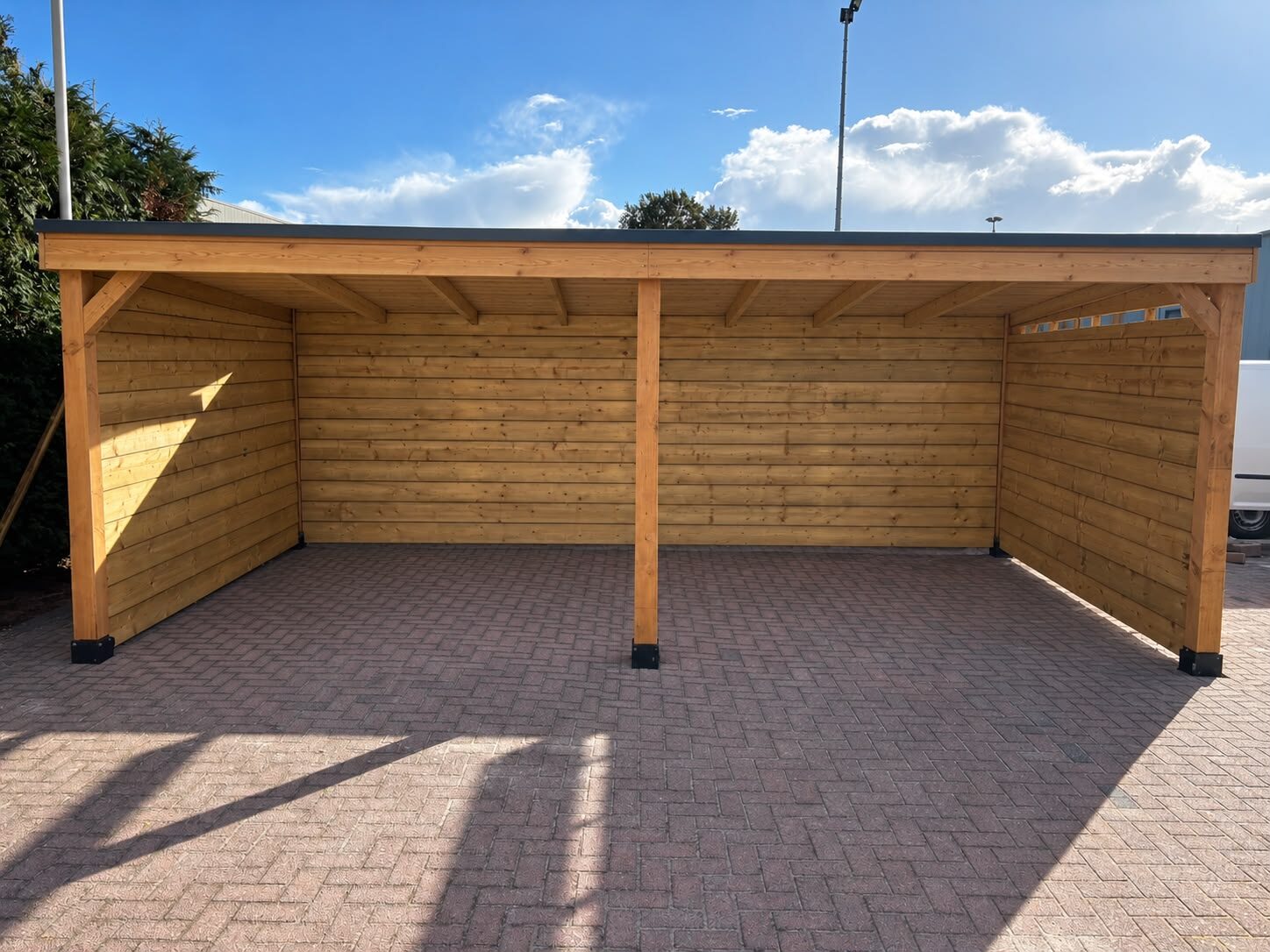 Ruime houten overkapping op bestrating, geschikt als carport