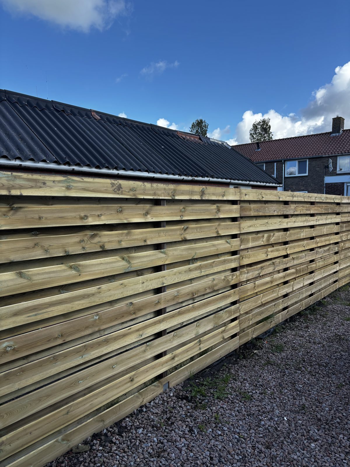 Horizontale grenen schutting langs een grindpad